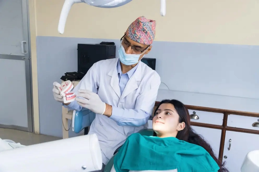 Dentist in Dhaka topi explaining dental treatment to a patient in a Nepal clinic